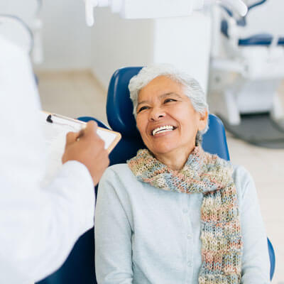 Elderly woman smiling at male dentist
